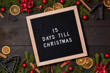 15 Days till  Christmas  countdown letter board on dark rustic wood background with Christmas decoration and fir branch frame top view flatlay