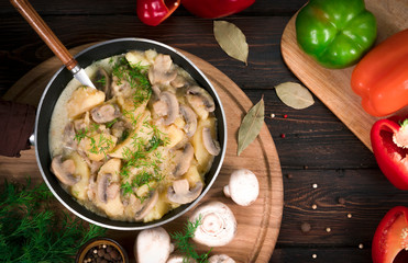 potatoes with mushrooms in a skillet on a wooden background