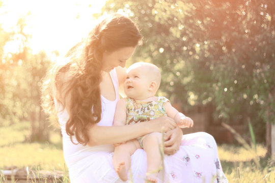 Mom Talking To The Baby Sitting On A Bench In The Park