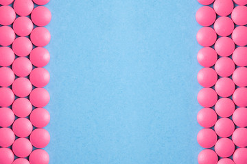 Lines of pink pills on blue background. Copy space.