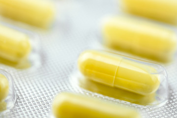 Packaging with yellow and white pills for treatment. Close up.