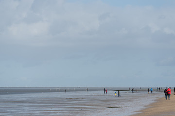 Fototapeta na wymiar people in a wide minimalistic wadden sea landscape
