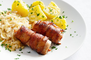 roasted bacon and rabbit belly rolls garnished with potato and cabbage sprinkled with parsley