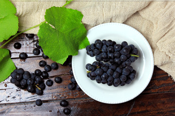 bunches of fresh grapes, inside ceramic dish, on rustic wooden table