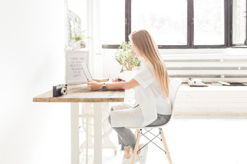 Young business woman working at home behind a laptop. Creative Scandinavian style workspace