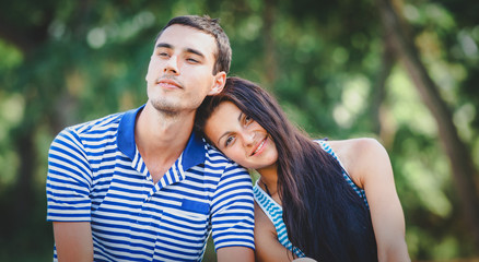 Portrait of a young couple in blue striped clothes in spring time season park.