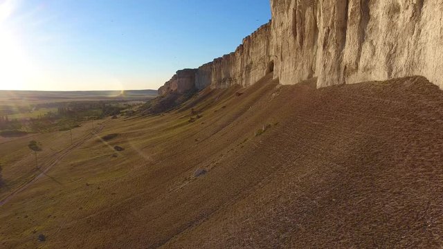 Aerial view drone shadow flying back over rocks, birds fly into camera, cape White Canyon, bright sun at sunset, cliffed Tropical 4K, cliffed coast line Crimea Rocks line.