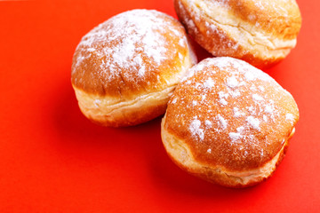 Tasty sweet donuts with powdered sugar on bright red background
