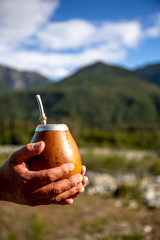 Man holding calabash yerba mate in nature. Travel and adventure concept. Latin American drink yerba...