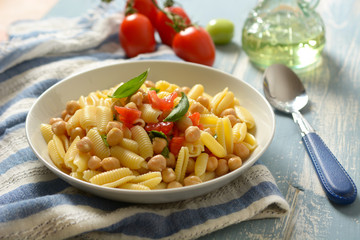 Italian gnocchi pasta with tomatoes, basil and chickpeas - closeup