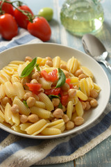 Italian gnocchi pasta with tomatoes, basil and chickpeas - closeup