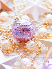Christmas and New Year star decorations on white knitted background. Metal light bulbs with delicate pattern, golden beads and violet balls.