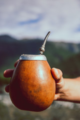 Man holding calabash yerba mate in nature. Travel and adventure concept. Latin American drink yerba mate