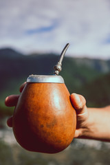 Man holding calabash yerba mate in nature. Travel and adventure concept. Latin American drink yerba...