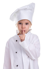 Smart adorable girl chef white uniform isolated on white background, holding a pointing finger near the lips. Hush sign. Portrait image