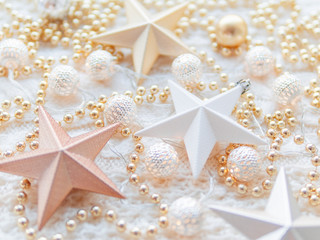 Christmas and New Year star decorations on white knitted background. Metal light bulbs with delicate pattern, pale beige beads.