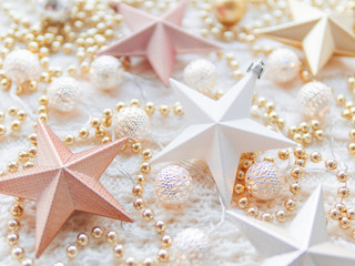 Fototapeta na wymiar Christmas and New Year star decorations on white knitted background. Metal light bulbs with delicate pattern, pale beige beads.