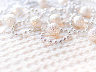 Christmas and New Year decorations on white knitted background. Metal light bulbs with delicate pattern, silver beads.