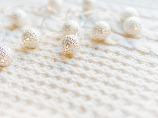 Christmas and New Year decorations on white knitted background. Metal light bulbs with delicate pattern