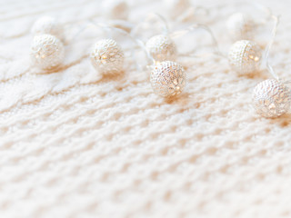 Christmas and New Year decorations on white knitted background. Metal light bulbs with delicate pattern