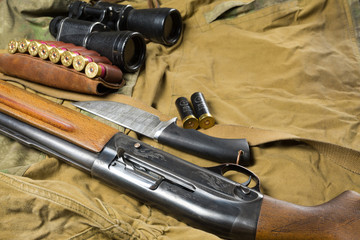 Hunting rifle and ammunition lie on wooden background.