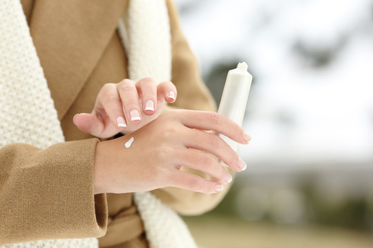 Woman hand hydrating skin applying cream in winter