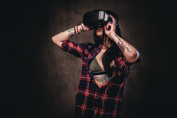 Tattooed girl wearing a red unbuttoned checked shirt wearing a VR headset.