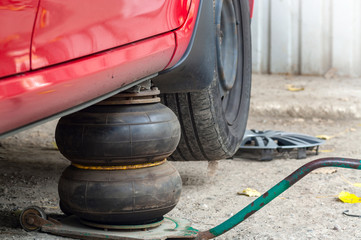 Replacing wheels on a car, pneumatic jack holds the body.