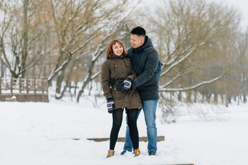 Fototapeta na wymiar Winter portrait of young beautiful happy smiling couple outdoors. Christmas and winter holidays. Man and woman in snowy park