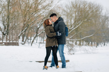 Fototapeta na wymiar Winter portrait of young beautiful happy smiling couple outdoors. Christmas and winter holidays. Man and woman in snowy park