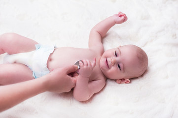 A very small child, a baby, lies back at the doctor's office and the doctor listens to the lungs, the heart.