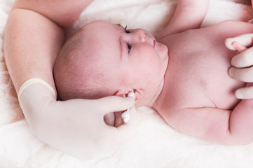 The child at the doctor's office and his ears are cleaned with a cotton swab.