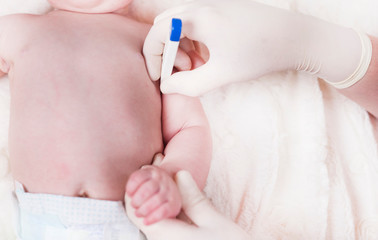 A small child, a baby who is measured temperature.