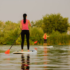 Back view of sporty woman on paddleboard at summer river