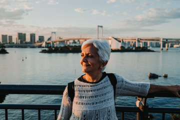 .Beautiful view of Tokyo Bay from the Odaiba district. Middle-aged woman taking pictures with her smartphone. Travel photography.