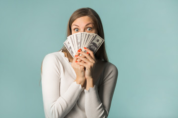beautiful young girl with dollars in hands on a blue background