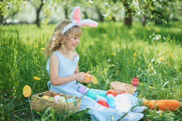 Obraz na płótnie Canvas Cute funny girl with Easter eggs and bunny ears at garden. easter concept. Laughing child at Easter egg hunt