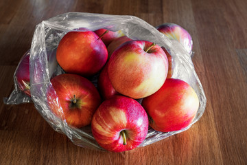 Apple fruit in plastic bag on wood table