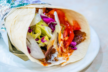 Shaurma on the plate. Meat with vegetables in a bread cake. Fast food