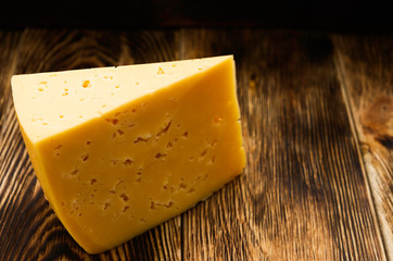 triangular piece of cheese on a wooden surface