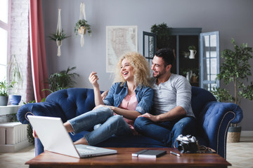 Young family planning a travel online with laptop sitting on a couch in the living room.