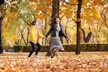 Obraz premium Two happy girls running in autumn city park.