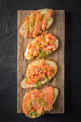 Bruschetta with sliced fish salmon, cucumber, arugula and young grass sprouts