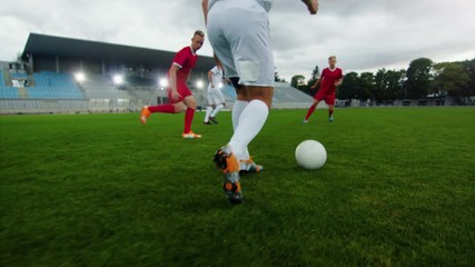 Professional Soccer Player Leads with a Ball, Masterfully Dribbling and Bypassing Sliding Tackles of His Opponents. Two Professional Football Teams Playing. Following Ground Shot. - Powered by Adobe