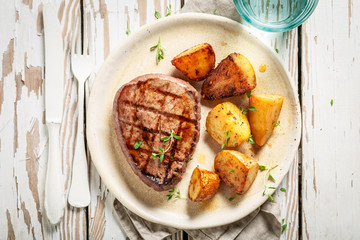 Delicious steak and roasted potatoes served with water on table