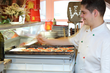 Kucharz przygotowuje małą pizze do pieczenia. © Stanisław Błachowicz