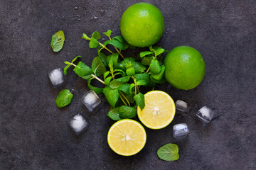 Fresh mint, lime and ice on a black background. Ingredient for mahito. Top view