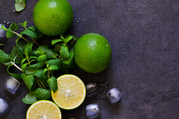Fresh mint, lime and ice on a black background. Ingredient for mahito. Top view