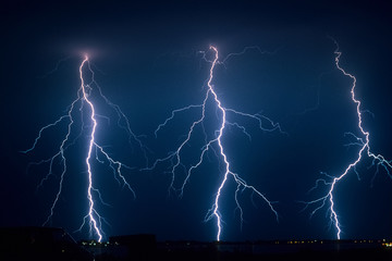 Three powerful lightningbolts strike down to earth from a severe thunderstorm in The Netherlands