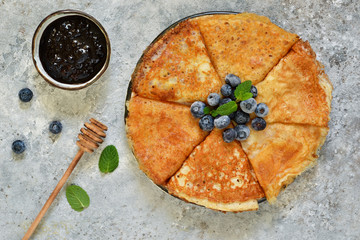 Thin pancakes with blueberry jam on a concrete background with poxt space.
